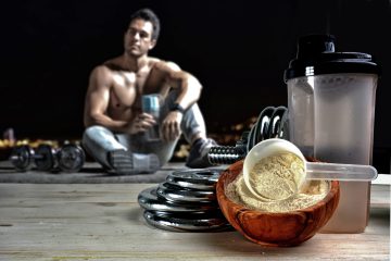 Protein shake Vanilla flavor accompanied by weights and sportsmen in the background